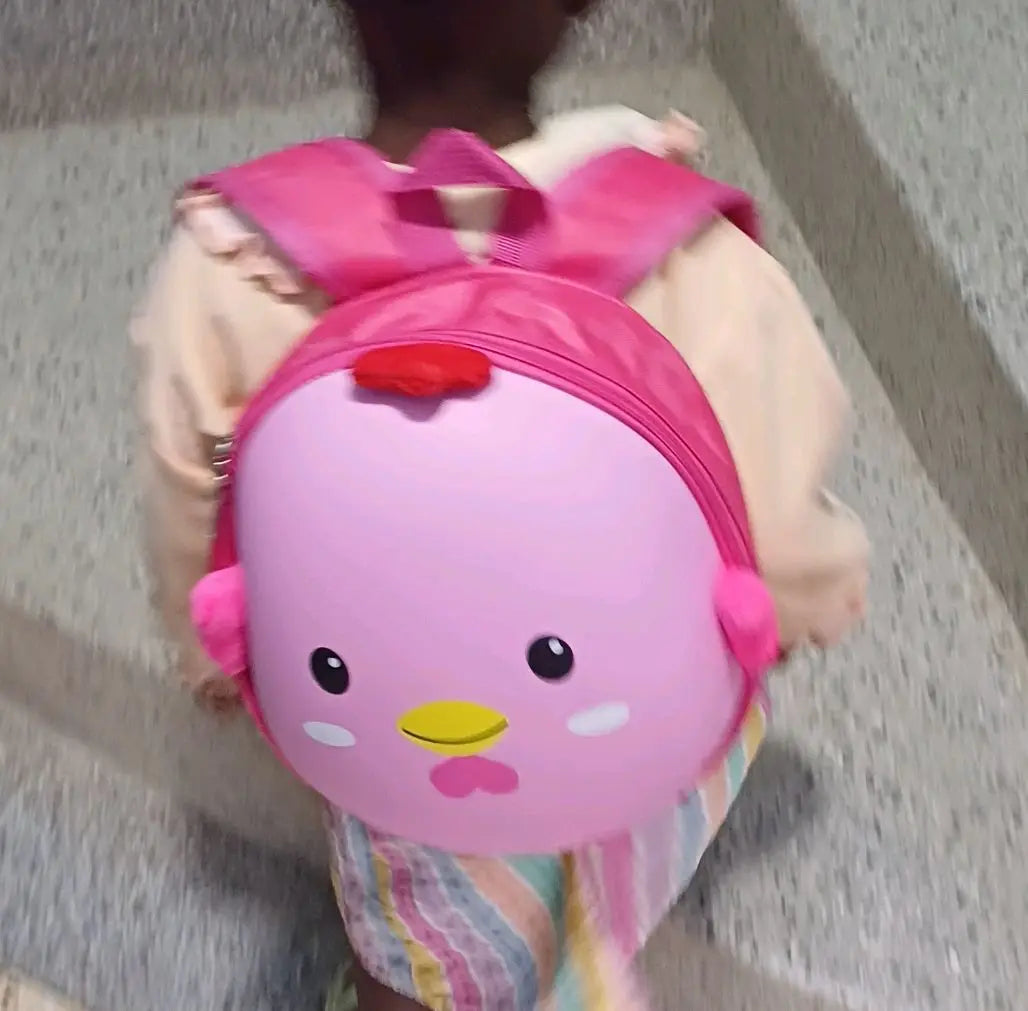 A toddler walking with the Blush Pink chick backpack on