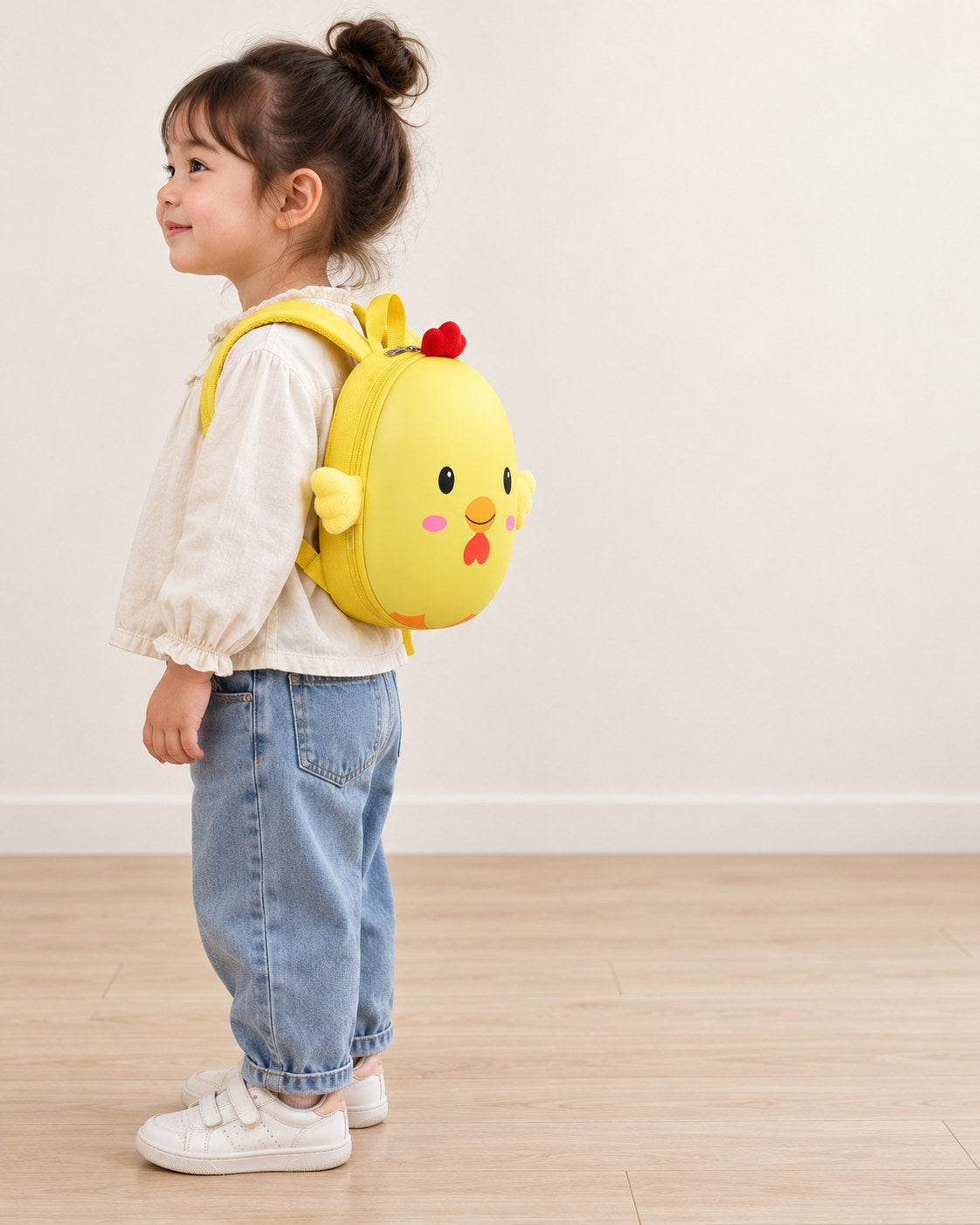 Side view of a child wearing the yellow chick backpack