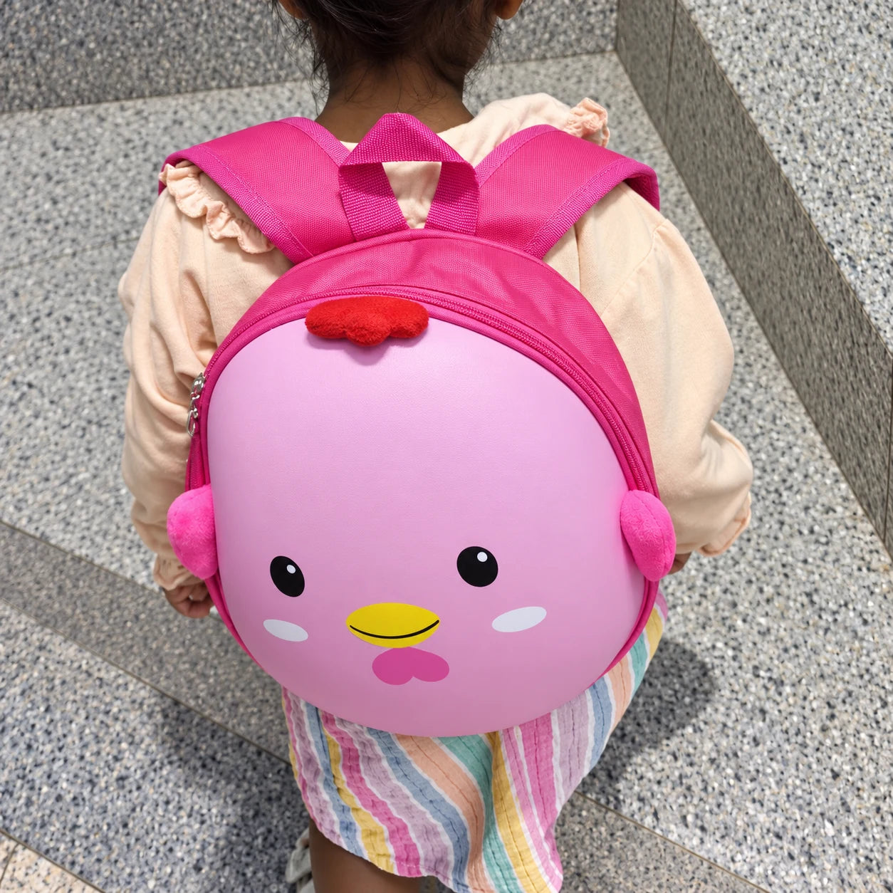 A toddler walking with the Blush Pink chick backpack on